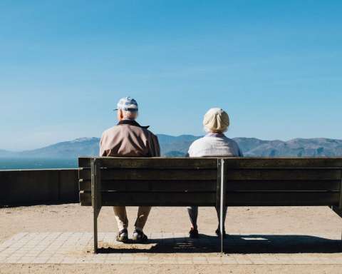 man and woman sitting on bench facing sea