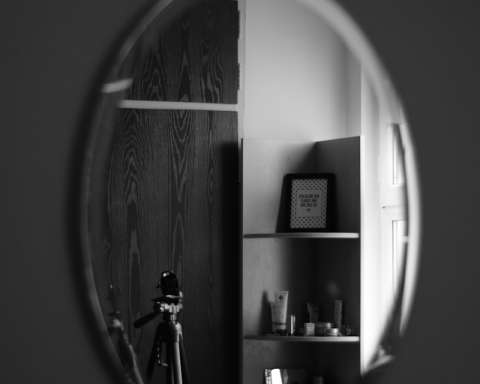 grayscale photo of man standing in front of mirror