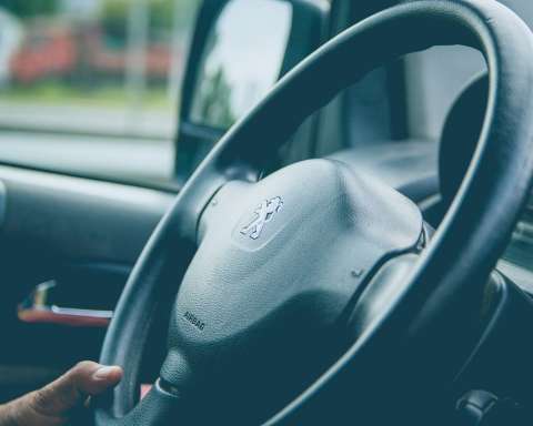 a steering wheel of a car with a hand on the steering wheel