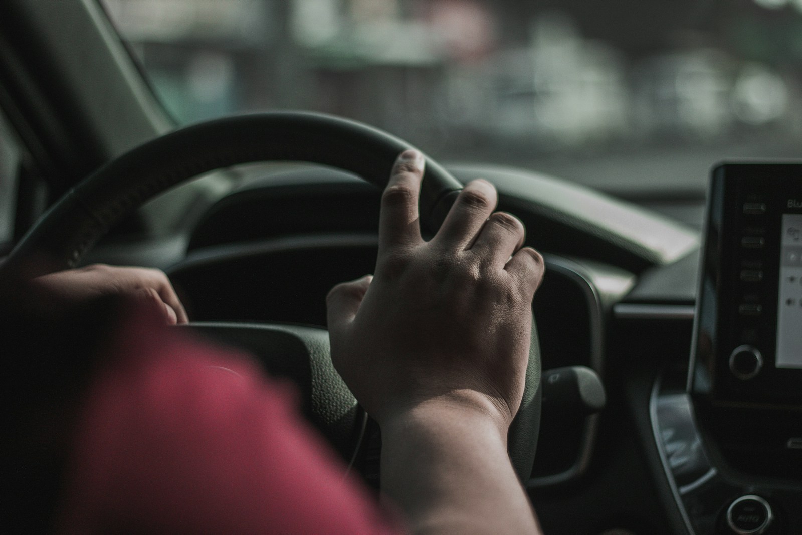 a person driving a car with their hand on the steering wheel